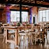 Wedding reception with farm table, cross back chairs, and table setting in an industrial venue.