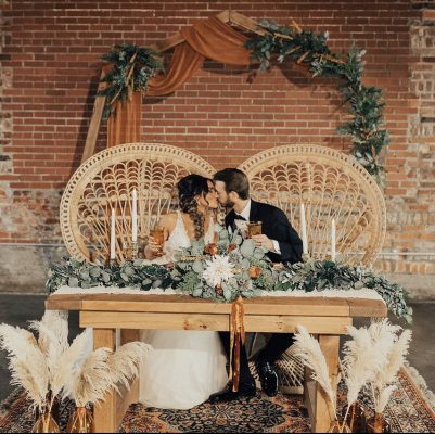 Couple sitting on peacock chairs kissing at an Indiana Rust Wedding