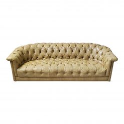 Pale yellow leather vintage sofa with tufted seat and curved arms.