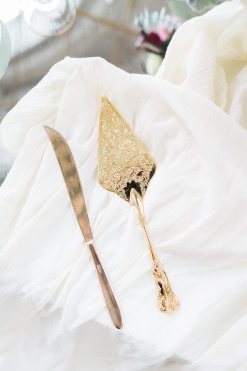 Gold cake server and knife on white linen