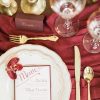 Gold and white china plates, gold flatware, vintage coups and brass candlesticks on a deep red drape
