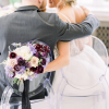 Couple with their backs to the camera sitting in clear chairs so you can see dress details