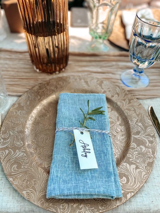 Gold charger with a blue napkin and light blue goblet