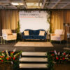 Navy sofa and pink chair rentals on a stage at a corporate event