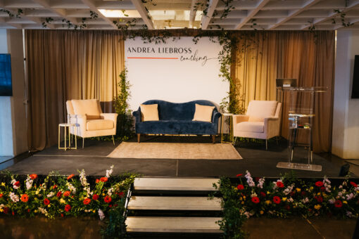 Navy sofa and pink chair rentals on a stage at a corporate event