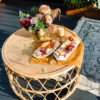 Top view of the Anay round rattan coffee table. Cheese and meat on marble trays and florals. Tori rug on the floor.