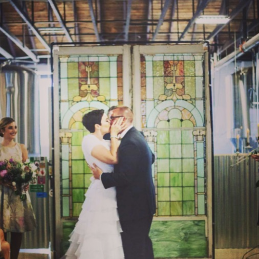 Multi-colored stained glass freestanding backdrop with a couple kissing at wedding ceremony