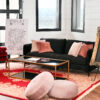Lounge area rental with black sofa, deep red velvet high back armchair, black glass coffee table, and red vintage rug.