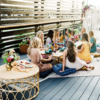 Women sitting on cushions around a low boho table having a picnic