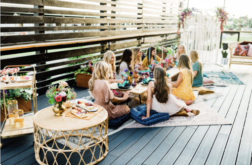 Women sitting on cushions around a low boho table having a picnic