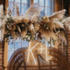 Close up on the back of the double throne peacock chair rental with neon initials K+L and florals hanging above