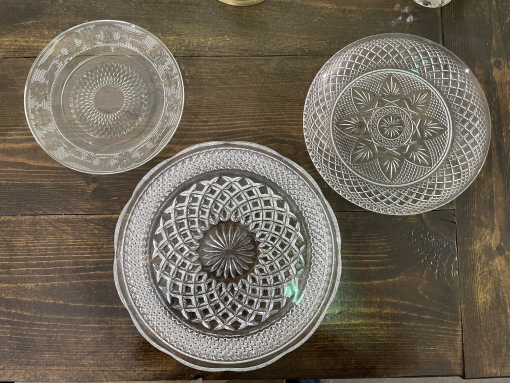 Set of 3 cut glass mismatched plates on a dark wood farm table