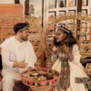 An ethnic cultural wedding with the couple sitting in rattan peacock chairs at their sweetheart table.