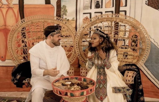 An ethnic cultural wedding with the couple sitting in rattan peacock chairs at their sweetheart table.