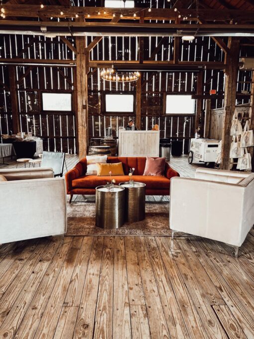 Burnt orange sofa with two boxy arm chairs on wooden floor at a barn.