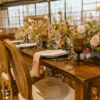 Solid wood farm table, french wooden chairs with cushions - set up for a wedding reception with florals and place settings