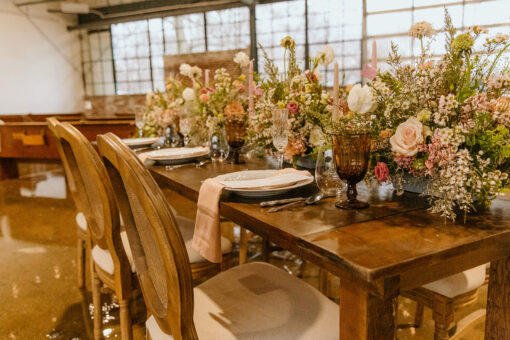 Solid wood farm table, french wooden chairs with cushions - set up for a wedding reception with florals and place settings