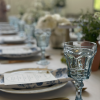 Mismatched blue goblets in focus with florals and long table in background at wedding reception