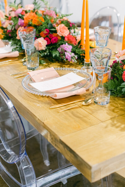 Tablescape with clear dinner plates, light blue goblets, orange candles with clear glass candlesticks.