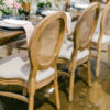 Cane backed wooden chairs at a wedding reception with dark wood farmtables.