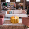 White sofa, two pink barrel chairs and a gold coffee table in a seating area in a wooden barn.