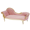 Side view of a pink chaise lounge with the left side set up for resting - higher arm and back. Cream and gold detailing on wood edges around the back and legs.