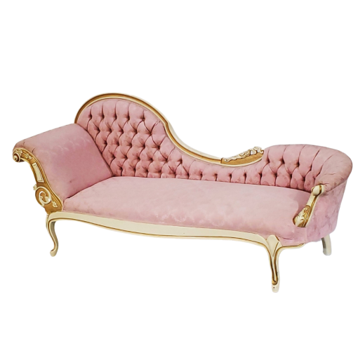 Side view of a pink chaise lounge with the left side set up for resting - higher arm and back. Cream and gold detailing on wood edges around the back and legs.