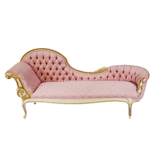 fainting sofa rental in a light pink fabric. High wave on the left flowing into a lower edge on the right. Left side has an arm for resting on. Tufted back and gold detailing.