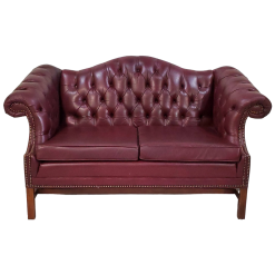 Maroon leather chesterfield sofa with tufted back, two cushions, and winged arms