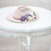 Top of the table with blue detailing. Hat with florals sitting on top.
