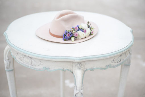 Top of the table with blue detailing. Hat with florals sitting on top.