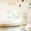 White serpentine sofa with a rattan coffee table against a large window with natural light.