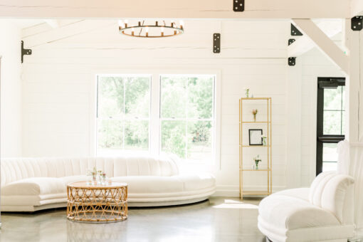 White serpentine sofa with a rattan coffee table against a large window with natural light.