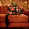 Rust colored mid-century modern velvet sofa with florals from a wedding.