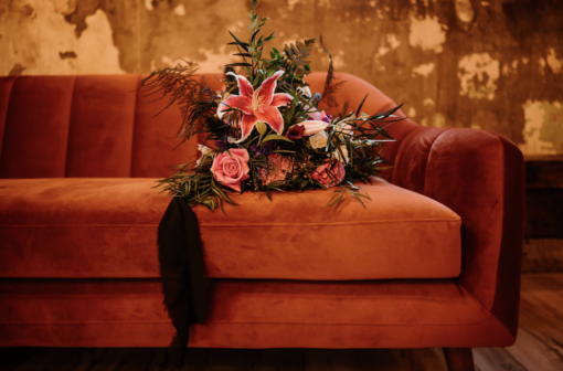 Rust colored mid-century modern velvet sofa with florals from a wedding.