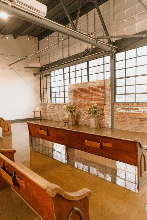 Church pews on shiny concrete floors in an industrial venue with windows and exposed brick.