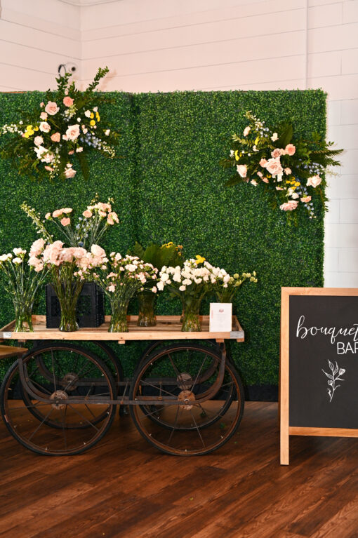 Vendor cart against a boxwood backdrop. Holding display of flowers in a bouquet bar
