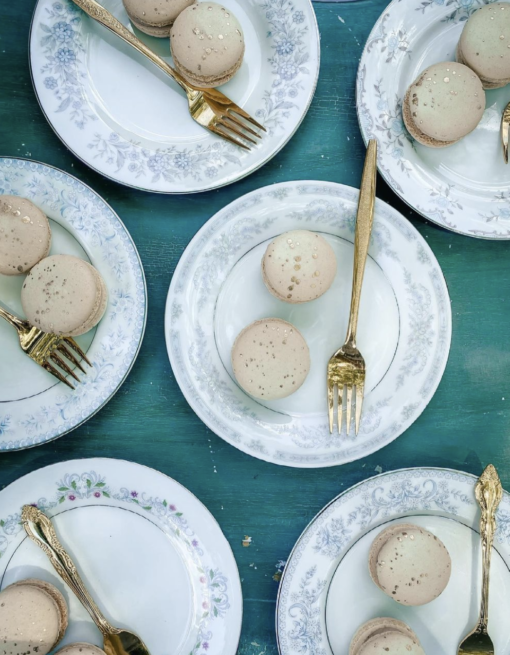 Vintage mismatched china plates with dessert and gold forks.