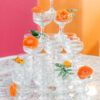 Vintage coupes used in a tower. Decorated with orange flowers. Top of vintage MCM table with white design and a glass top.
