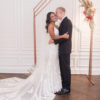 A young diverse couple standing in from of the Colleen Copper arch for a wedding ceremony.