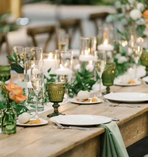 Wedding reception tablescape with farm tables, cylinder candle holders and olive mismatched goblets.