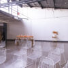 White wire chairs set up in a semi-arch on a concrete floor