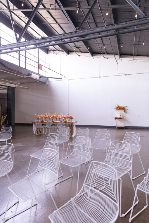 White wire chairs set up in a semi-arch on a concrete floor