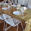 6 White wire modern chairs around a solid wood farm table