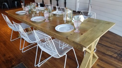 6 White wire modern chairs around a solid wood farm table