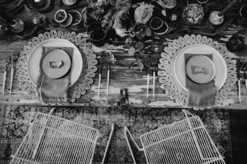 Black and white arial photo of a sweetheart table at a wedding reception. Boho tablescape and white wire modern chairs