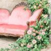 Angle view of the loveseat with heavy green and pink florals draping the back and down the side