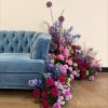Quarter of blue velvet sofa with pink and purple florals on the floor and crawling up the side