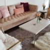 Lounge seating rentals featuring a pink sofa with pillows, a white coffee table, a modern rug, rattan chair, and dramatic white chair