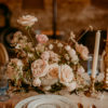 Wedding reception table setting with china, blue goblets, candles and florals